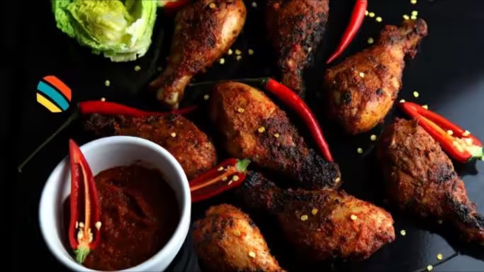 Grilled peri-peri chicken drumsticks with red chillies and a bowl of peri-peri sauce