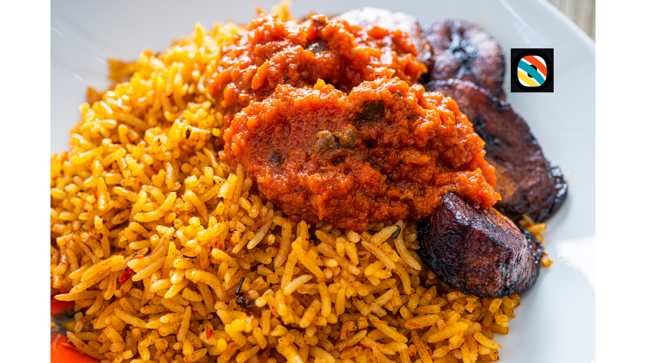 A plated serving of Nigerian jollof rice with vegetables and fresh greens